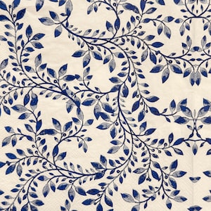 May include: A cream-colored napkin with a repeating pattern of blue and gray leaves and vines. The leaves are detailed with shading, and the vines curve across the surface, creating a decorative design. The napkin is likely made of paper.