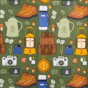 May include: A green patterned paper featuring camping-themed illustrations. The design includes brown hiking boots, a blue thermos, a brown backpack, a yellow lantern, a compass, and a camera.