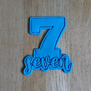 May include: Blue plastic cookie cutter shaped like the number 7 with the word "seven" written underneath.