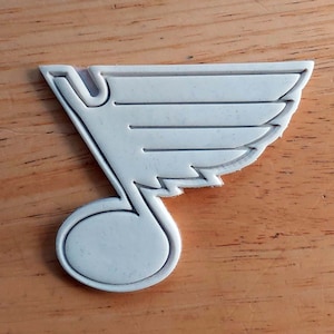 May include: White plastic cookie cutter shaped like a musical note with a wing design.