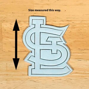 K&ouml;nnte beinhalten: Wei&szlig;er Plastik-Ausstecher in Form des Logos der St. Louis Cardinals. "Size measured this way." steht &uuml;ber dem Ausstecher.
