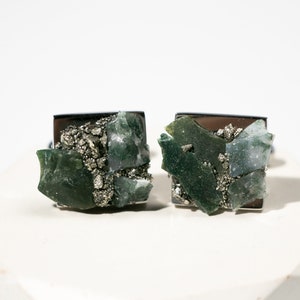 May include: A pair of cufflinks featuring green and gray agate and pyrite stones set in silver.
