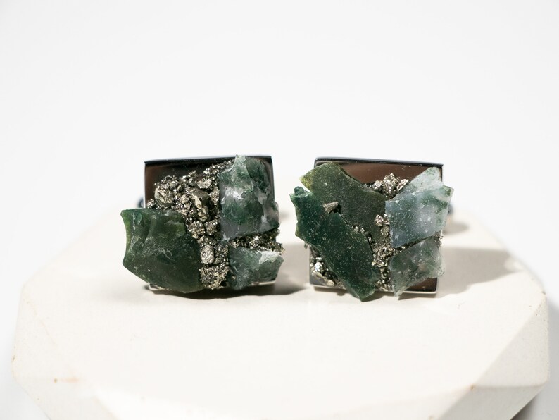 May include: A pair of cufflinks featuring green and gray agate and pyrite stones set in silver.