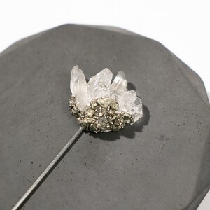 May include: A silver pin with a cluster of clear quartz crystals and a base of pyrite.