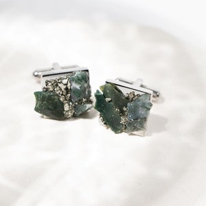 May include: A pair of silver cufflinks with green and gray agate and pyrite stones.