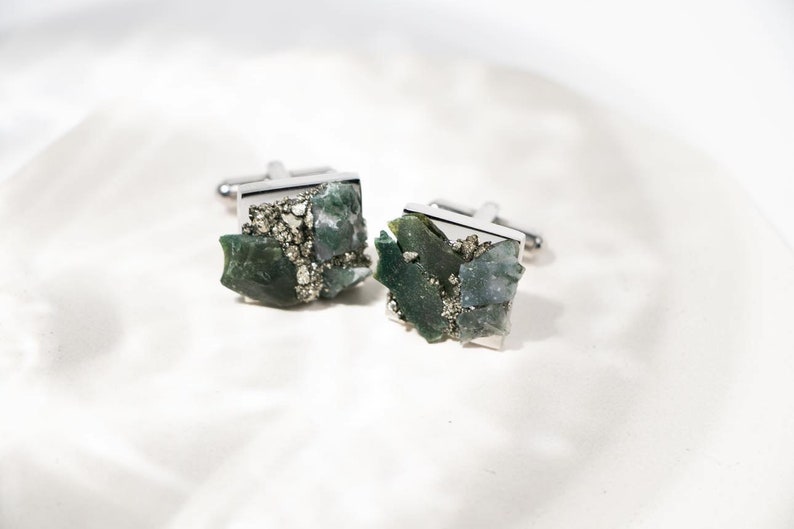 May include: A pair of silver cufflinks with green and gray agate and pyrite stones.