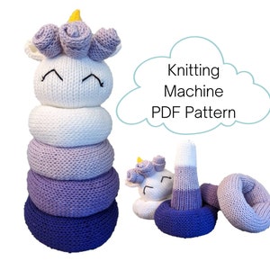 May include: Knitting machine PDF pattern for a purple and white unicorn stacking toy. The toy is made of knitted fabric and has a unicorn head with a yellow horn and pink flowers on top. The toy is made up of five rings, with the bottom ring being the largest and the top ring being the smallest. The rings are stacked on top of each other, with the unicorn head on top of the smallest ring.