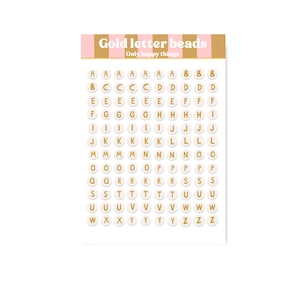 Może przedstawiać: Arkusz okrągłych białych koralików ze złotymi literami od A do Z. Nagłówek zawiera tekst Gold letter beads Only happy things na różowo-beżowym paskowanym tle. Koraliki są ułożone w siatkę na białym podłożu, tworząc czytelny zestaw liter.