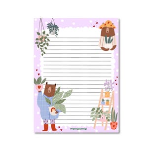 Op de afbeelding: Een gelijnd notitieblok met een lichtpaarse achtergrond en een geschulpte rand. Het notitieblok bevat illustraties van beren met planten, een ladder met planten en hangplanten. De tekst "Onlyhappythings" staat onderaan.