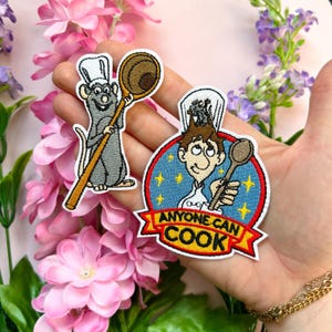 Può includere: Due toppe ricamate da stirare con personaggi del film d'animazione Ratatouille. La prima toppa mostra Remy il ratto che tiene un cucchiaio di legno. La seconda toppa mostra Linguini, uno chef, che tiene un cucchiaio e uno sfondo a forma di stella con il testo "Anyone Can Cook".