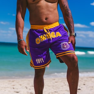 Pantalones cortos Omega Psi Phi morados bordados con rayas doradas