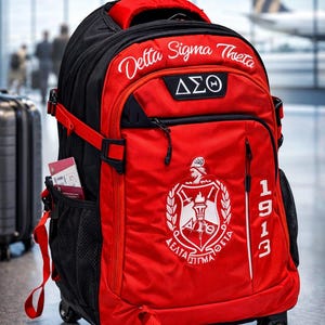 May include: A red and black rolling backpack featuring the text Delta Sigma Theta, the Greek letters &Delta;&Sigma;&Theta;, and a crest emblem. The bag includes the year 1913 printed vertically on the front, a retractable handle, wheels, and side mesh pockets.
