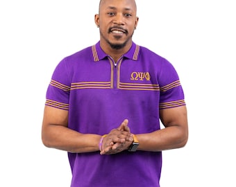 May include: A purple polo shirt with gold stripes on the collar and sleeves. The shirt has a zipper and the Greek letters ΩΨΦ embroidered on the chest. The person is wearing a watch and a purple bracelet.