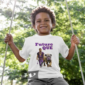 Puede incluir: Una camiseta blanca con un gráfico morado de una persona joven con un perro. El texto "Future Que" está impreso en morado en la camiseta.