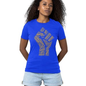 May include: A royal blue t-shirt with a gold fist graphic. The fist is made up of text, including the names of historically Black colleges and universities.