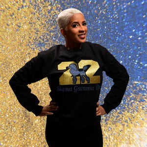 May include: Black sweatshirt with gold glitter lettering that says "22" and "Sigma Gamma Rho". A blue rhinestone poodle is inside the number "22".
