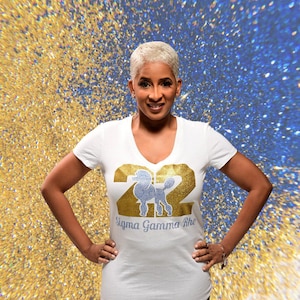 May include: White t-shirt with a gold number 22 featuring a blue rhinestone poodle and the text "Sigma Gamma Rho".