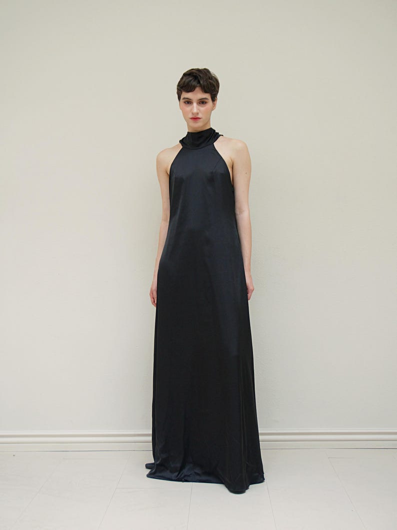 May include: A black halter-neck maxi dress with a simple, sleek design.