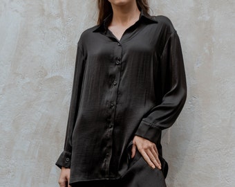 Dit zwarte zijden kraagoverhemd/minimalistische blouse met lange mouwen