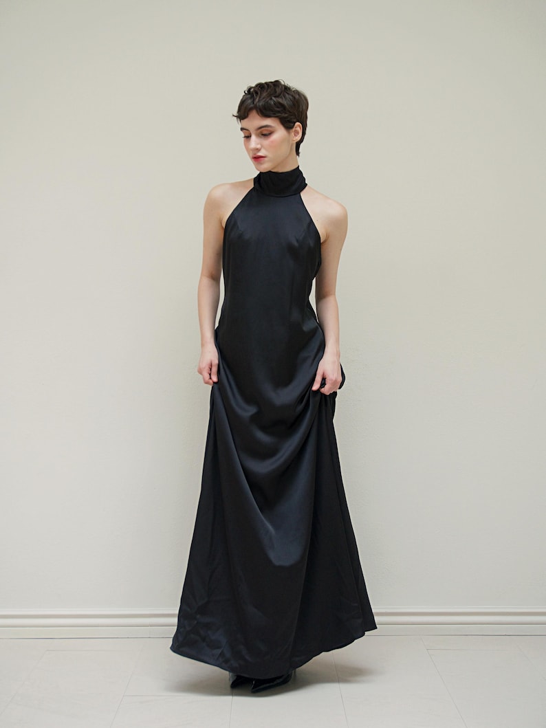 May include: A black halter-neck maxi dress with a high neckline and a flowing skirt.
