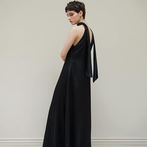 May include: A black maxi dress with a halter neckline and a long, flowing skirt. The dress has a tie at the back of the neck.