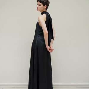 May include: A black halter-neck maxi dress with a long, flowing skirt and a tie at the back of the neck.