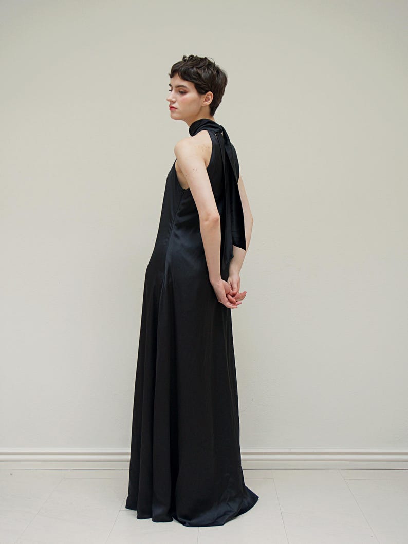 May include: A black halter-neck maxi dress with a long, flowing skirt and a tie at the back of the neck.