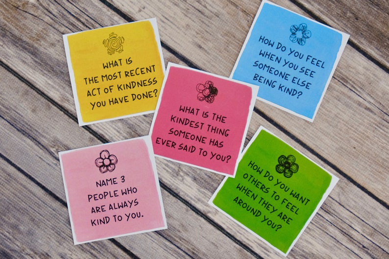 K&ouml;nnte beinhalten: F&uuml;nf bunte Karten mit Aufforderungen f&uuml;r ein Gespr&auml;chsstarterspiel. Die Karten sind gelb, rosa, blau, gr&uuml;n und rot. Jede Karte hat ein Blumendesign und eine Frage zur Freundlichkeit.