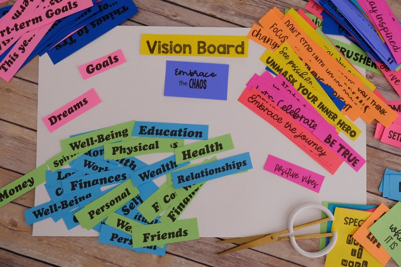 Peut inclure: Un tableau blanc avec les mots "Vision Board" &eacute;crits en noir sur une bande jaune. Le tableau est entour&eacute; de bandes de papier color&eacute;es avec des mots comme "Dreams", "Goals", "Well-Being", "Education", "Health", "Relationships", "Embrace the Chaos", "Unmask Your Inner Hero", "Be True", et "Positive Vibes".