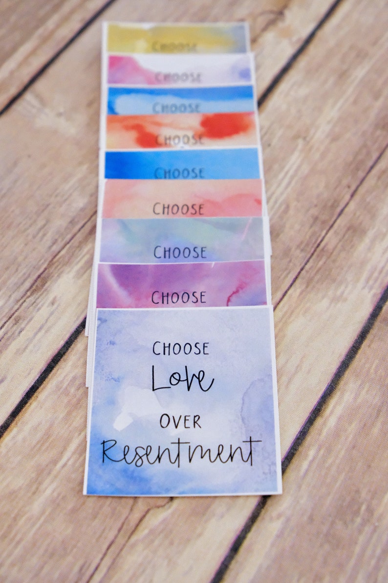 May include: A stack of colourful cards with the words "Choose Love Over Resentment" on the bottom card. The cards have a watercolour background.