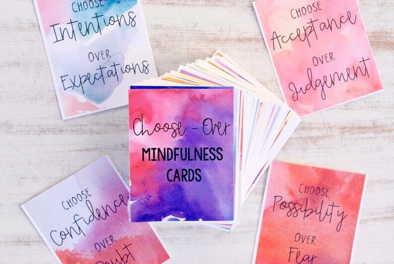 May include: A set of watercolour-style mindfulness cards with the text "Choose-Over Mindfulness Cards". The cards feature phrases like "Choose Intentions Over Expectations" and "Choose Acceptance Over Judgement".