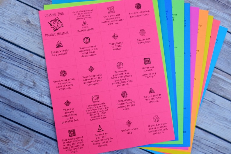 May include: A stack of colorful cards with positive messages printed on them. The cards are pink, orange, yellow, green, blue, and light blue. The messages include "Speak kindly to yourself", "Your happiness depends on the quality of your thoughts", "Believe in yourself. You have everything you need to accomplish what you want", "Never say "I can't". Always say "I'll try."