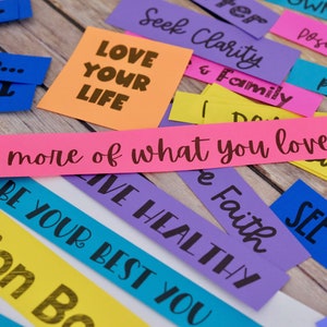 Peut inclure: Des bandes de papier color&eacute;es avec des phrases de motivation comme "Aime ta vie", "Cherche la clart&eacute;", "Fais plus de ce que tu aimes", et "Sois le meilleur de toi-m&ecirc;me".