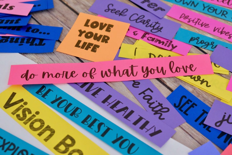 Peut inclure: Des bandes de papier color&eacute;es avec des phrases de motivation comme "Aime ta vie", "Cherche la clart&eacute;", "Fais plus de ce que tu aimes", et "Sois le meilleur de toi-m&ecirc;me".