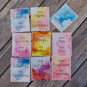 May include: Nine watercolour cards with inspirational quotes. Each card features a different colour scheme and a quote about choosing a positive mindset. The quotes include "Choose Intention over Chance", "Choose Passion over Indifference", "Choose Grace over Perfection", "Choose the Future over the Past", "Choose Strength over Weakness", "Choose Hope over Fear", "Choose Intentions over Expectations", "Choose Confidence over Doubt", and "Choose Acceptance over Comparison".