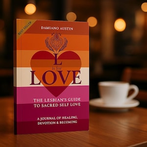 May include: A book with a cover featuring the text "L is for LOVE" in a heart shape, with the colours of the lesbian pride flag. The book is titled "THE LESBIAN'S GUIDE TO SACRED SELF LOVE" and "A JOURNAL OF HEALING, DEVOTION & BECOMING."