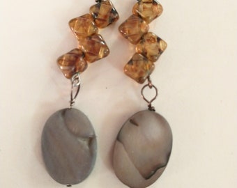 May include: A pair of dangle earrings with brown and clear glass beads and a large oval shaped shell pendant.