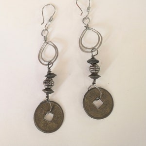 Handmade earrings made with hammered silver tear drop shapes and brass Chinese coins.