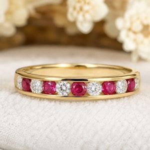 Può includere: Un anello a fascia in oro con rubini e diamanti rotondi alternati. Le pietre preziose sono incastonate in un canale, creando una fila continua di scintillio rosso e bianco. L'anello ha una finitura lucida e liscia. L'anello misura circa 0,2 cm di larghezza.
