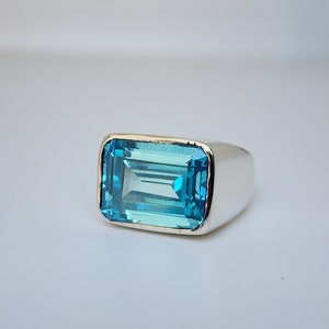Puede incluir: Un anillo de plata con una gran piedra rectangular de topacio azul claro.