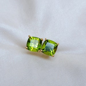 Puede incluir: Un par de pendientes de oro con piedras preciosas de peridoto verdes cuadradas.