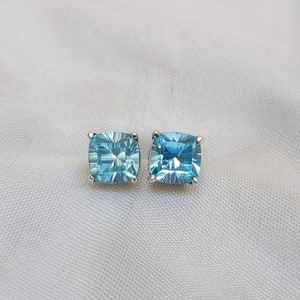 May include: A pair of silver stud earrings with square-shaped blue gemstones.