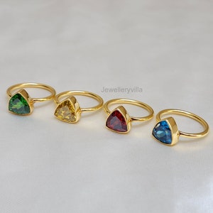 Puede incluir: Cuatro anillos de oro con piedras preciosas triangulares. Los anillos presentan una piedra preciosa verde, amarilla, roja y azul.