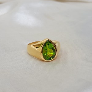 May include: A gold ring with a pear-shaped green gemstone.