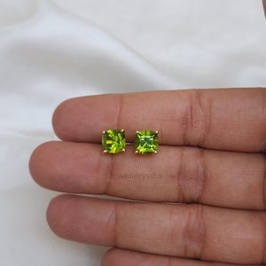 May include: A pair of gold earrings with square green peridot gemstones.