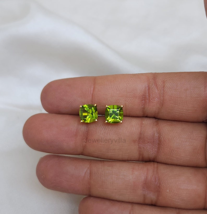 May include: A pair of gold earrings with square green peridot gemstones.