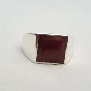 Peut inclure: Une bague en argent avec une pierre carr&eacute;e rouge fonc&eacute;.