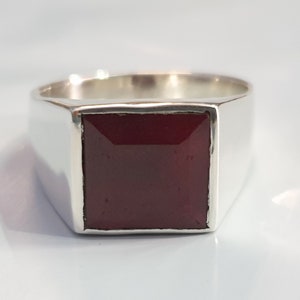 Peut inclure: Une bague en argent avec une pierre carr&eacute;e rouge fonc&eacute;.