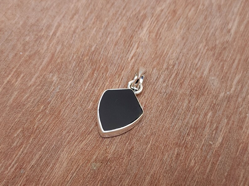 May include: A black onyx pendant in a silver shield shape.