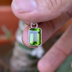 Puede incluir: Un colgante de plata con una piedra preciosa verde. La piedra preciosa est&aacute; tallada en forma de esmeralda.